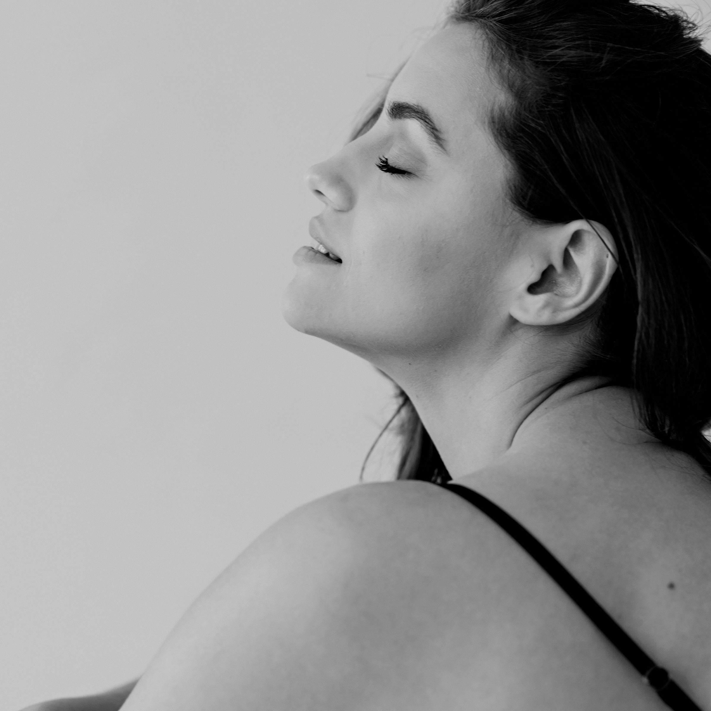 Woman with brown hair sitting on the floor and enjoying the sell of an essential oil.