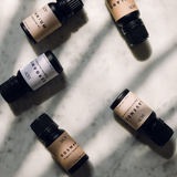 Verschiedene Aromaöle in schwarzen Fläschchen, wie Rosmarin, Lavendel, Thymian, Geranium liegen auf dem Boden.